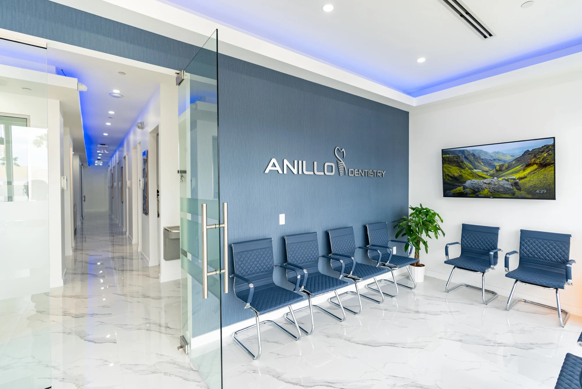 Anillo Dentistry — Glass partition and corridor beside the waiting room, under a blue cove light