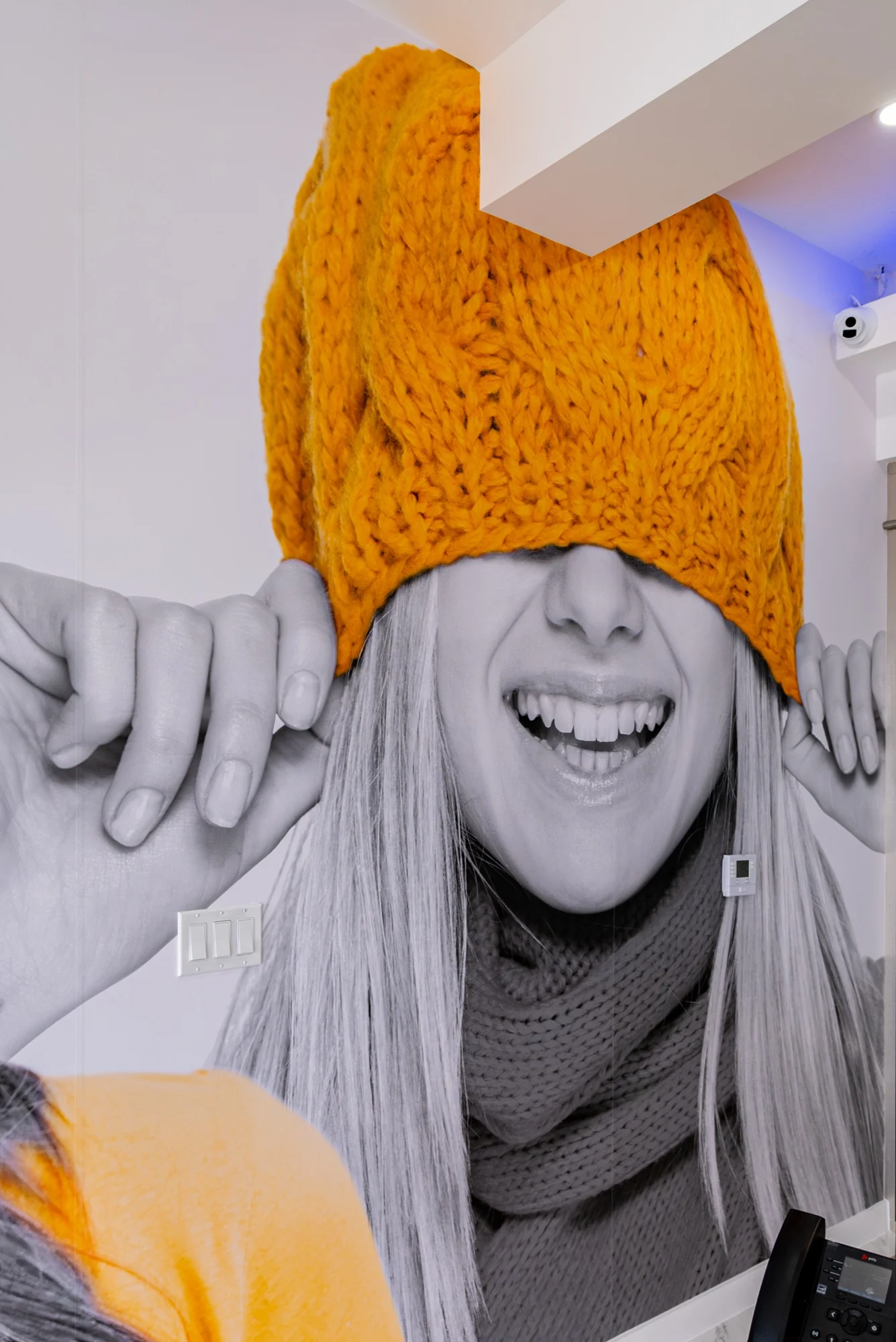 Anillo Dentistry — Close view of the mural: a laughing face under a yellow knit hat pulled over the eyes