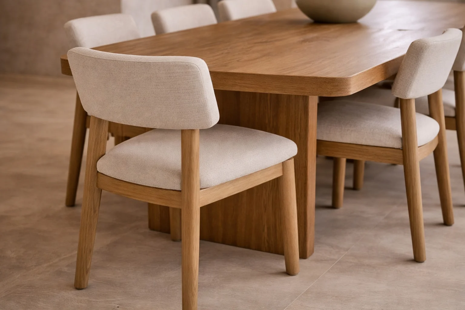 Casa Sienna — Close-up of a wood dining table with cream upholstered chairs on rounded wood legs