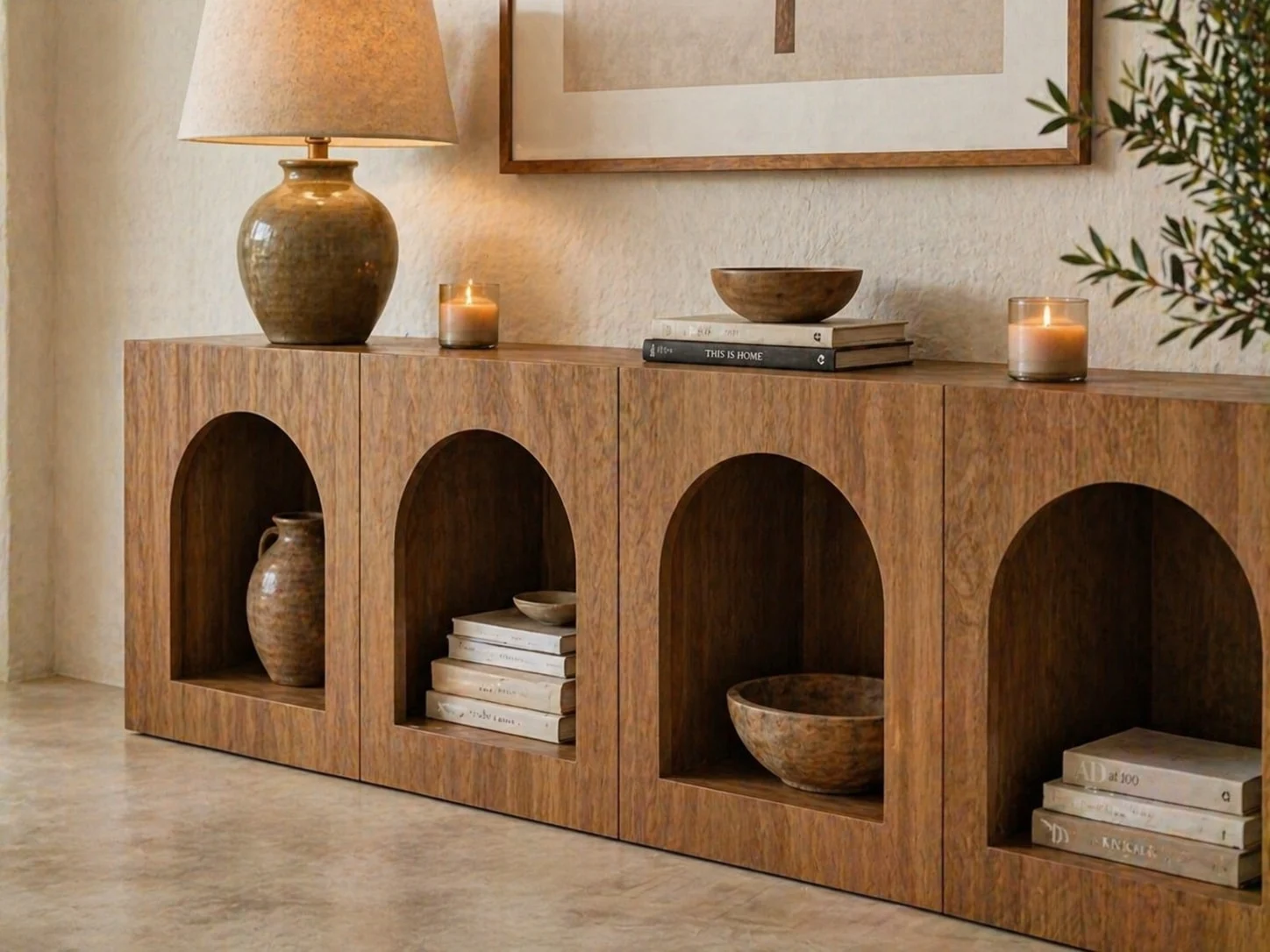 Casa Solenne — Detail of a wood sideboard with arched openings, a ceramic table lamp, stacked books and bowls