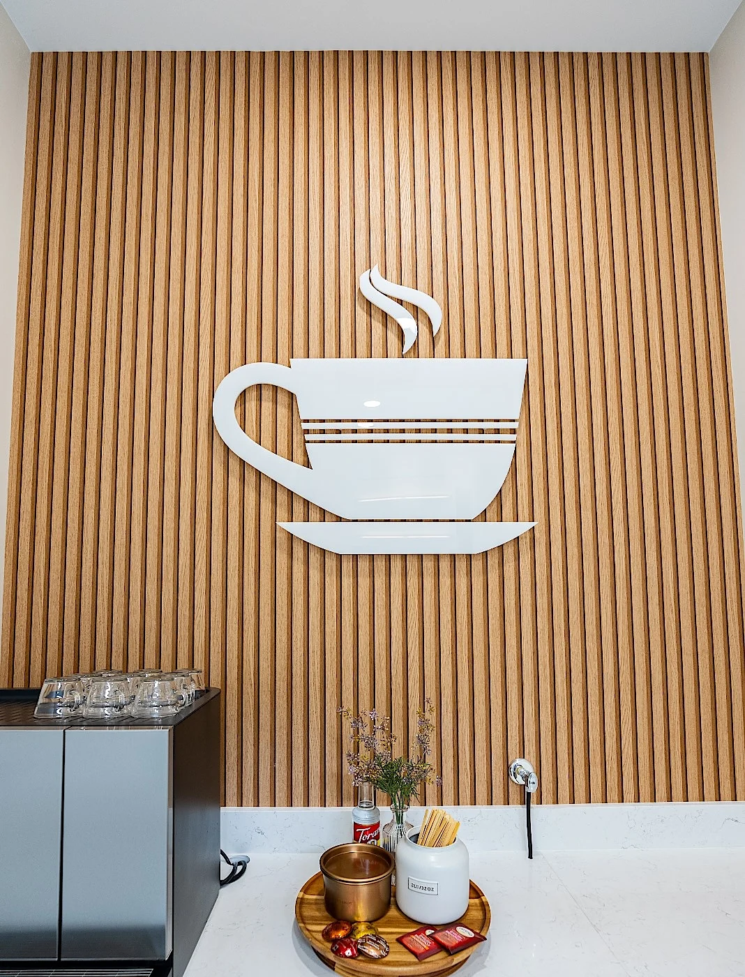 Clear Smiles Dental — Coffee station with a white cup sculpture on an oak slat wall
