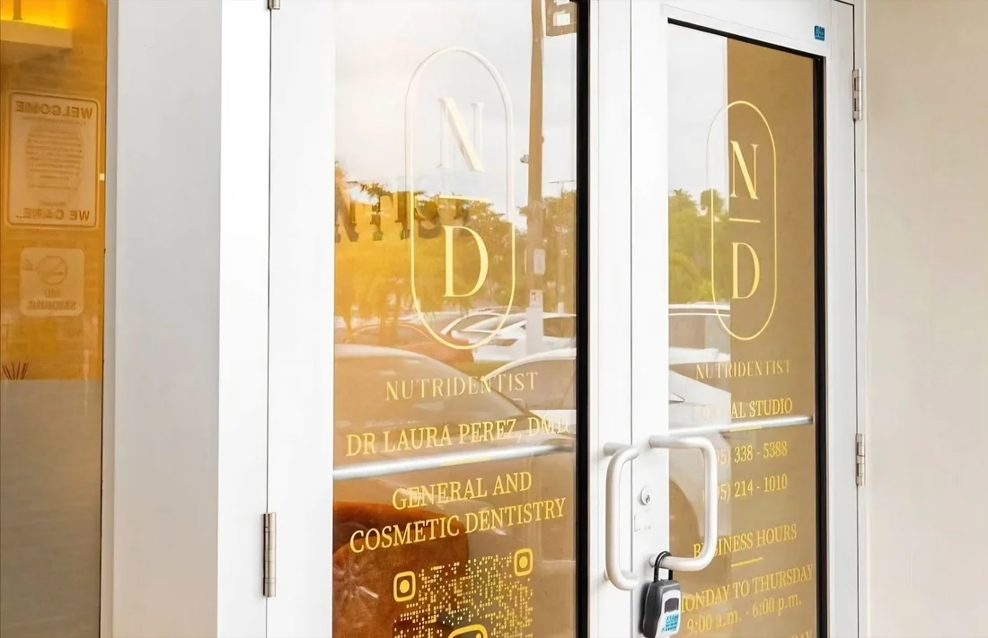 Nutridentist — Entrance doors with the gold N/D monogram, the practice name and its hours lettered on the glass