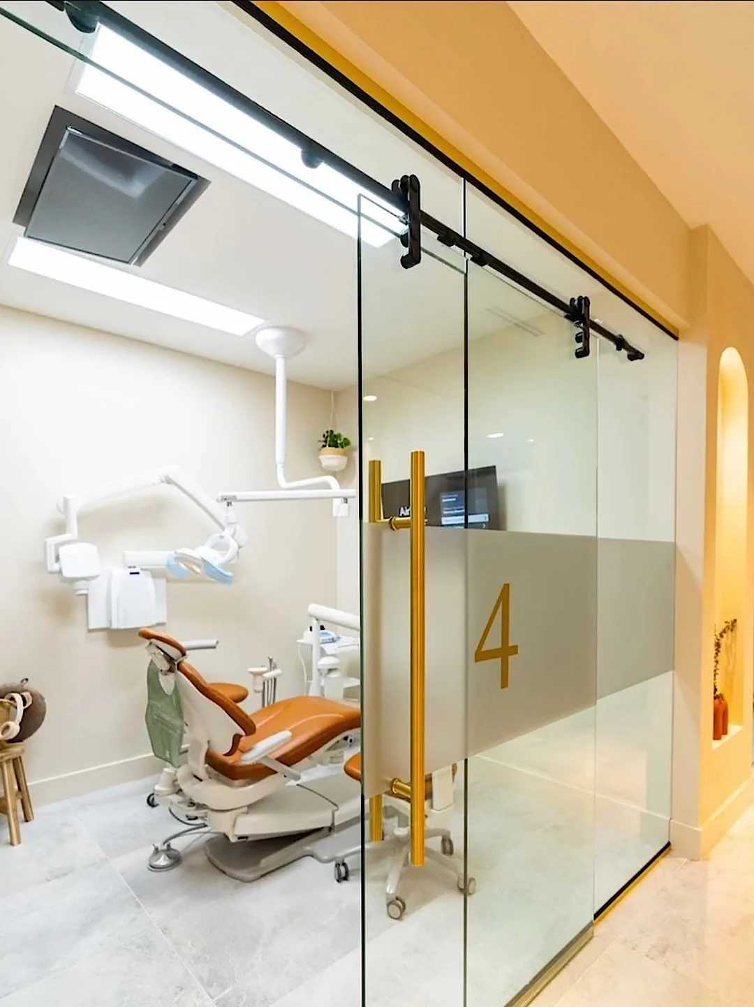 Nutridentist — Sliding glass door marked 4 with gold pulls, in front of a treatment room with a rust dental chair