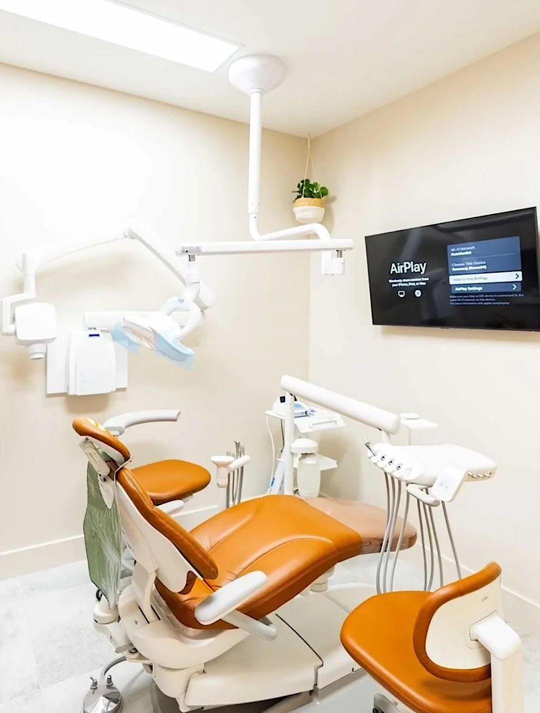 Nutridentist — Treatment room with a rust dental chair, a ceiling-mounted light and a wall screen