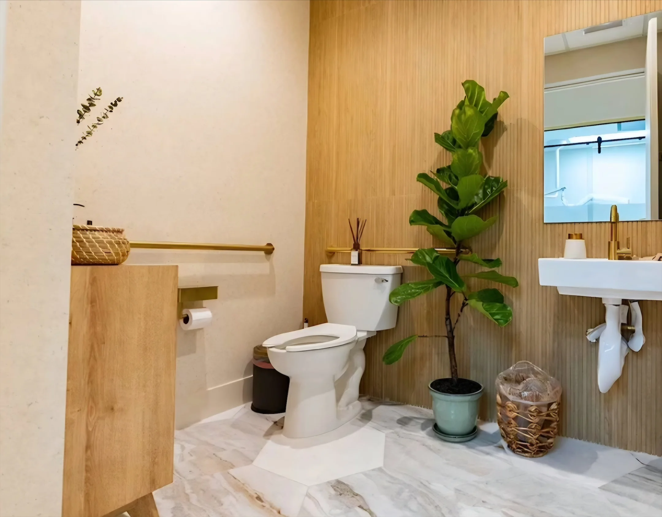 Nutridentist — Restroom with a wood-texture wall, a wall-hung sink with a gold faucet and a potted fig tree