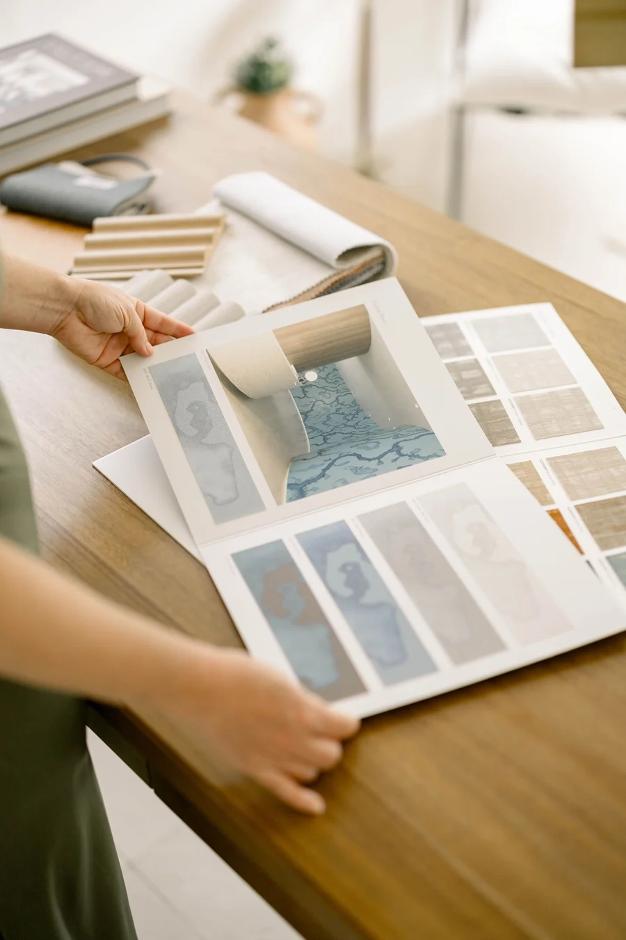 Hands laying out color and material boards on a wooden desk