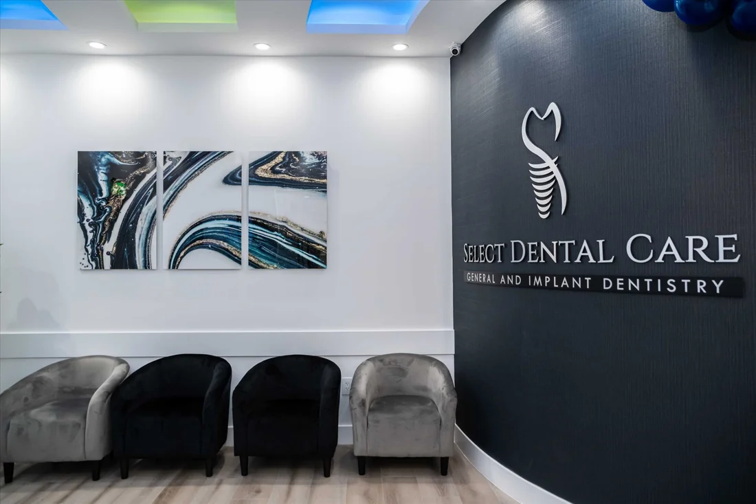 Select Dental Care — Reception with the practice name on a dark wall, an agate triptych and gray and black velvet chairs