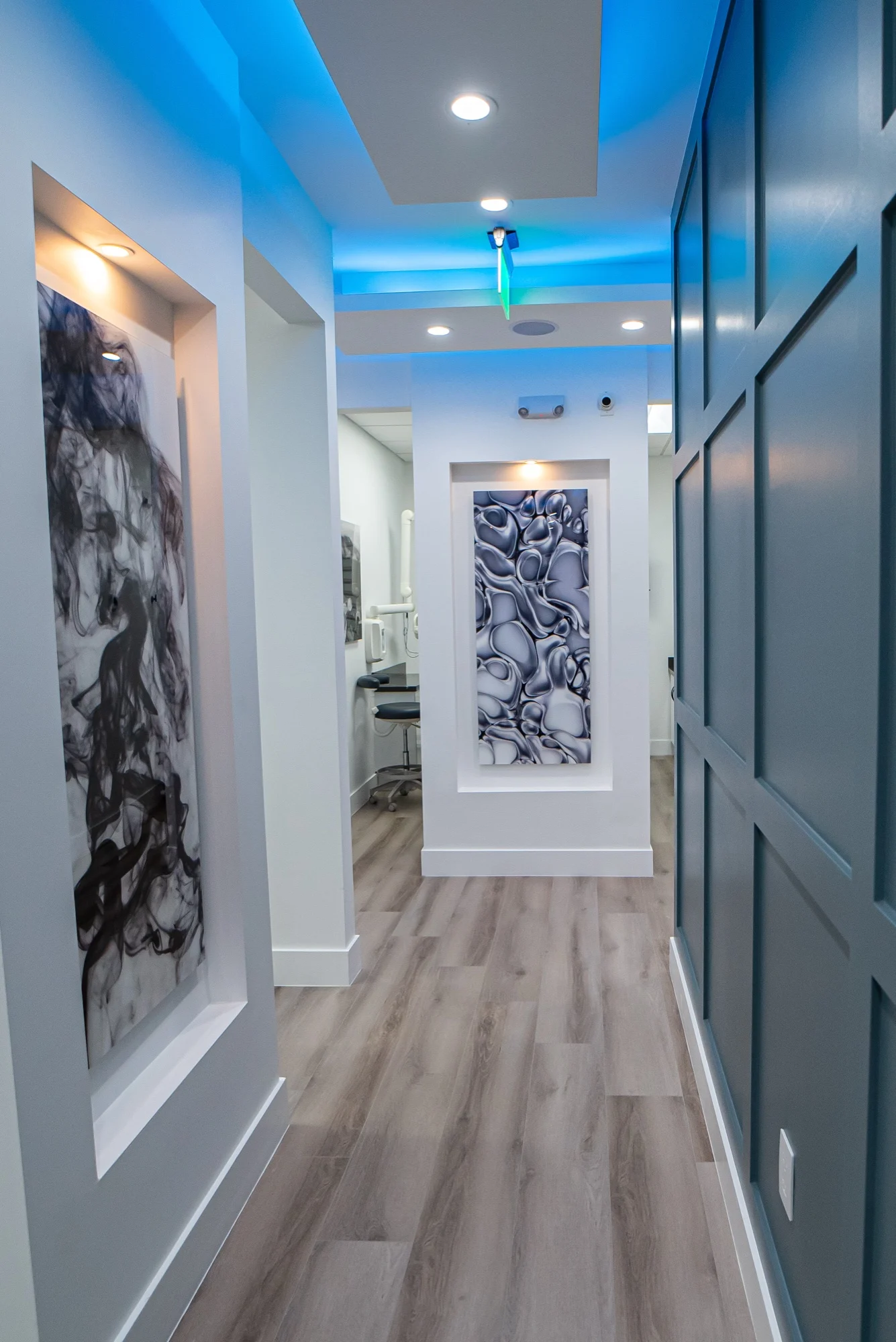 Select Dental Care — Corridor with a dark paneled wall on one side and lit art niches ahead