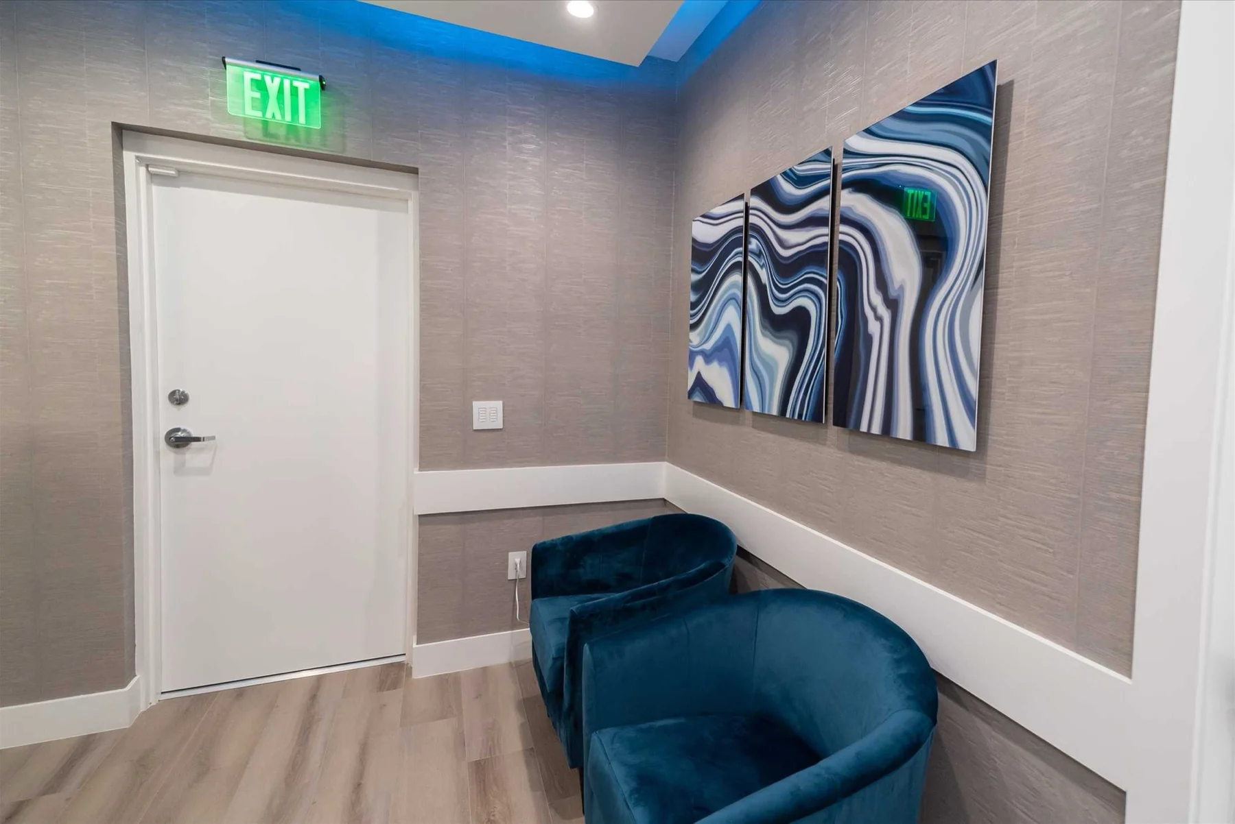 Select Dental Care — Waiting corner with blue velvet tub chairs under a blue-and-white agate triptych