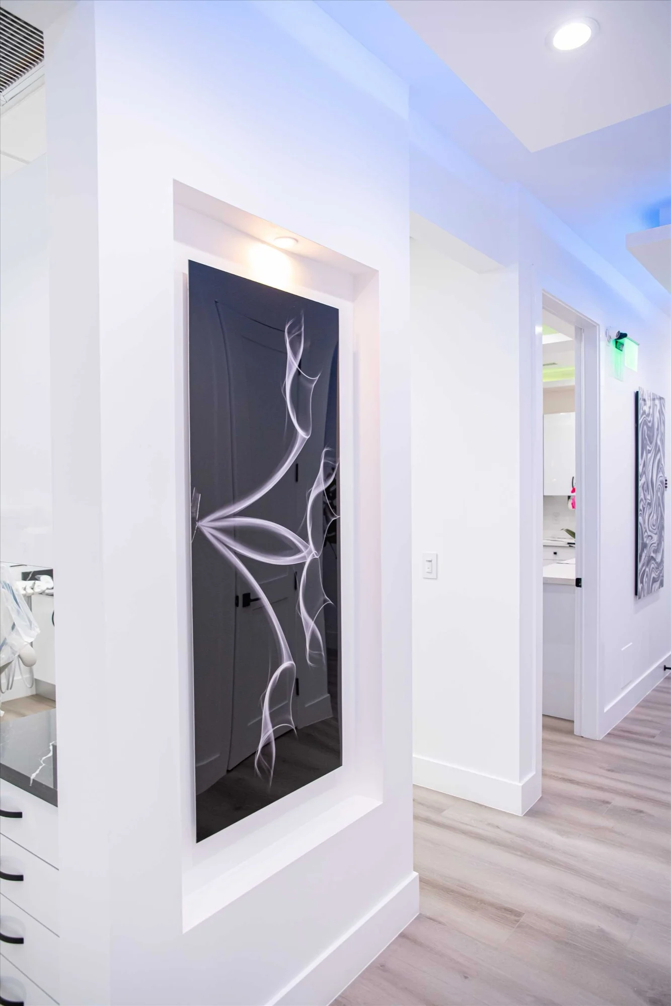 Select Dental Care — Black panel with a white line drawing in a lit niche along the corridor